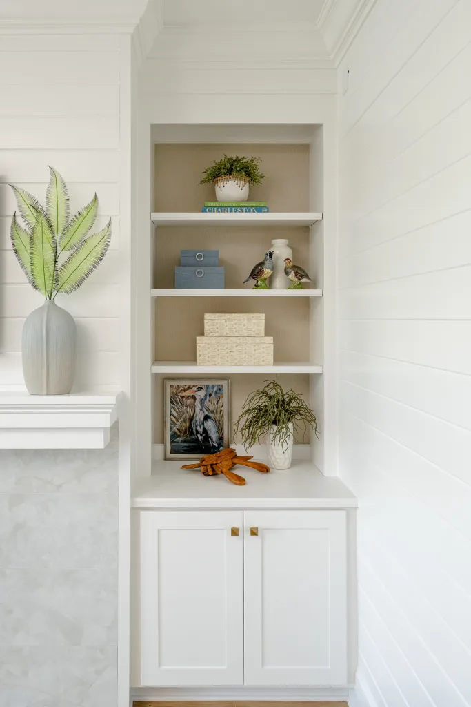 Built-in shelving styled with botanical art, ceramic quail, and palm-leaf vase in Charleston, SC